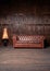 Brown leather sofa in wooden apartment interior against background of wooden wall. Big vintage couch with cozy luminous