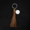 Brown Leather Tassel key ring on black wooden background. Fashion leather key chain for decoration