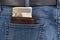 A brown leather wallet filled with 200 PLN Polish banknotes inserted into the back pocket of blue denim pants.