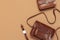 Brown leather women bag, stylish wristwatch on brown beige background top view flat lay copy space. Fashionable women`s