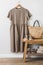 Brown linen women\\\'s summer dress on a hanger on the wall, straw bag on a bench, shoes in the interior of the dressing room