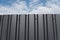 Brown metal plate against blue cloudy sky. Siding. Seamless surface of galvanized steel. Industrial building wall made