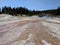 Brown orange ground and Black Pool at Yellowstone National Park