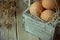 Brown Organic Eggs on Straw in Vintage Wooden Box on Plank Kitchen Table. Small Bouquet of Beige Dry Flowers. Easter Composition
