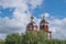 Brown Orthodox Church of Presentation of the Lord with bell tower and spire, round dome and gilded Orthodox crosses, behind trees