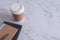 Brown paper cup of coffee with black book, textbook or diary on white marble desk with copy space. Photo concept of branding and