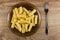 Brown plate with cooked pasta, fork on table. Top view