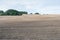 Brown ploughed field under cloudy sky after harvest