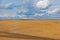 Brown plowed non-seeded field on a background of blue summer sky. sunny sky over an empty meadow. serenity, bliss. desktop