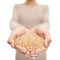 Brown rice grains natural food closeup in open hands. Woman showing uncooked raw rice grain in studio