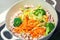 Brown rice with organic unmixed peeled sliced vegetables cooking in cast iron saucepan. Bright broccoli, carrot and