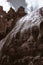 Brown rock peaks with waterfall and big clouds behind