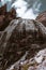 Brown rock peaks with waterfall and big clouds behind