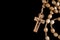 A brown rosary lying on a black background