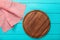 Brown round cutting board for pizza on red plaid tablecloth. Blue wooden background in the restaurant. copy space. Top view.