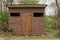 Brown rural wooden shed stands in green garden