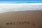 Brown sand beach with written word Welcome