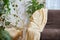 A brown sofa with beige capes in a living room with a flower and a window with curtains. Interior and Home decor