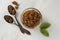 Brown sugar isolated in glass bowl, over styled marble background. Mint leaves. Top view, copy space