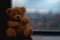 Brown teddy bear embraces, a romantic scene through rain kissed glass