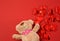 Brown teddy bear and red textile small hearts on red background