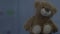 Brown teddy bear sitting behind rainy window, lighting blinking, childhood
