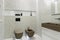 Brown toilet and bidet. Modern wc interior. Stylish brown sink, chrome faucet, large mirror. Shelf with bathroom accessories and a