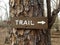 Brown trail sign with arrow on tree trunk