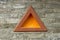 A brown triangle with a yellow center on a gray brick wall. brushed wall texture.