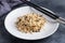 Brown and unpeeled rice on a plate with chopsticks. Dark concrete background. Copy space.