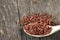 Brown unpeeled rice on a wooden spoon