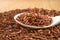 Brown unpeeled rice on a wooden spoon against a blurred background