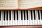 Brown upright piano keyboard with blurred sheet music.