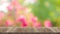 Brown vintage wooden table desk and copy space on bokeh image abstract blurred backgrounds from pink flower blossom and green