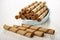 Brown wafer rolls in bowl, three wafer rolls on wooden table