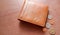 Brown wallet with coins on wooden floor.