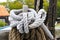 Brown and white braided ropes tied around a post at a marina - selective focus with bokeh background