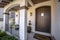 Brown wood arched front door with glass panes at the facade of home with porch