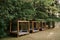 Brown wooden beach tents stand in the woods. Grey beach sofas