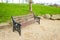 Brown wooden bench with a green meadow in the background. Lonely chairs on the lawn in the park.