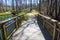 A brown wooden bench over a pond in the garden surrounded by lush green grass with a smooth footpath