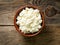 Brown wooden Bowl of homemade curd on dark brown wooden background, top view, close up