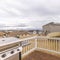 Brown wooden deck with white railing overlooking yard homes and cloudy sky