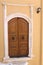 Brown wooden door set in a stucco archway