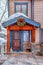 Brown wooden door and window at the snowy gabled entrance of home with wreath