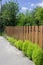 Brown wooden fence with green shrubs bushes in countryside