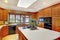 Brown wooden kitchen interior with white ceiling and skylight.