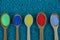 Brown wooden spoons with colored powder on blue stones