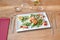 Brown wooden table and plate with shrimp and cheese croquettes on tomato and salad