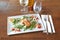 Brown wooden table and plate with shrimp and cheese croquettes on tomato and salad